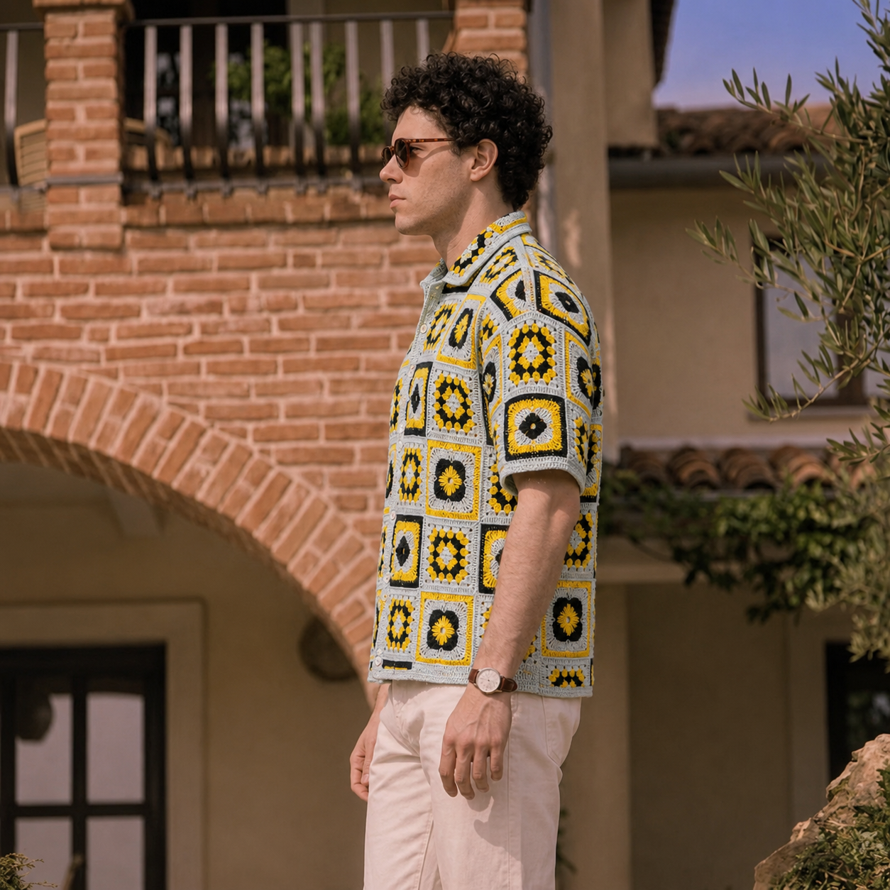 Side view of a man wearing a yellow, black, and gray granny-square crochet shirt